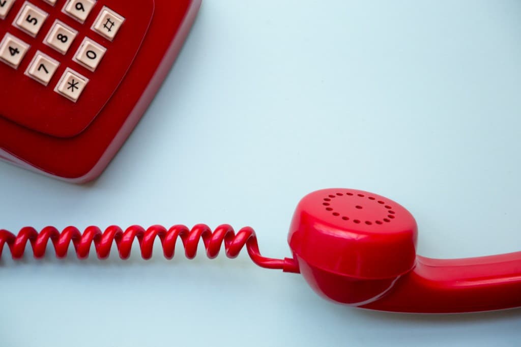 Téléphone rouge dont le combiné est décroché.