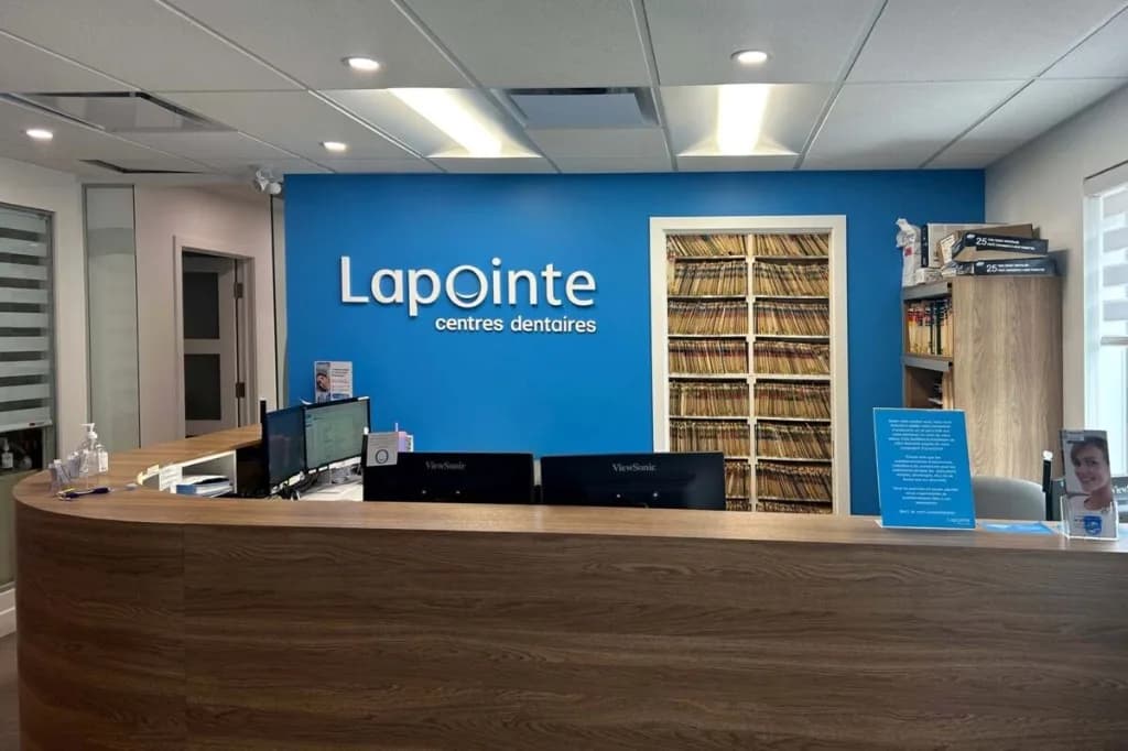 Réception d'une clinique Lapointe centres dentaires, avec le mur bleu de la marque et le comptoir en bois.