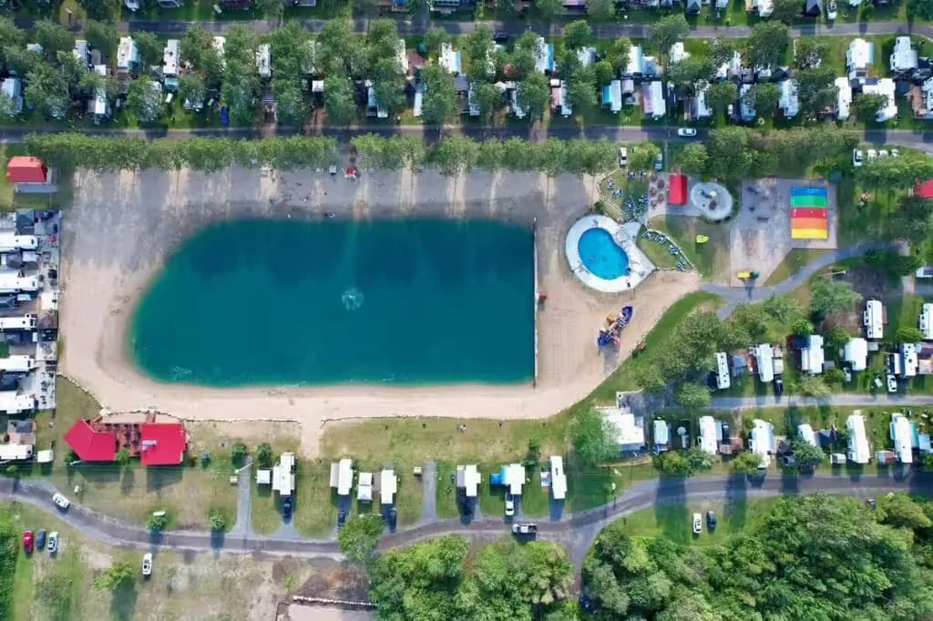 Aerial view of a campground, with a lake, a pool, and recreational vehicles.